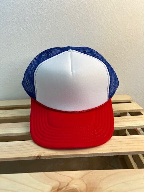 A red, white and blue hat sitting on top of a wooden bench.