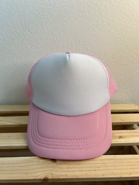 A pink and white hat sitting on top of a wooden table.